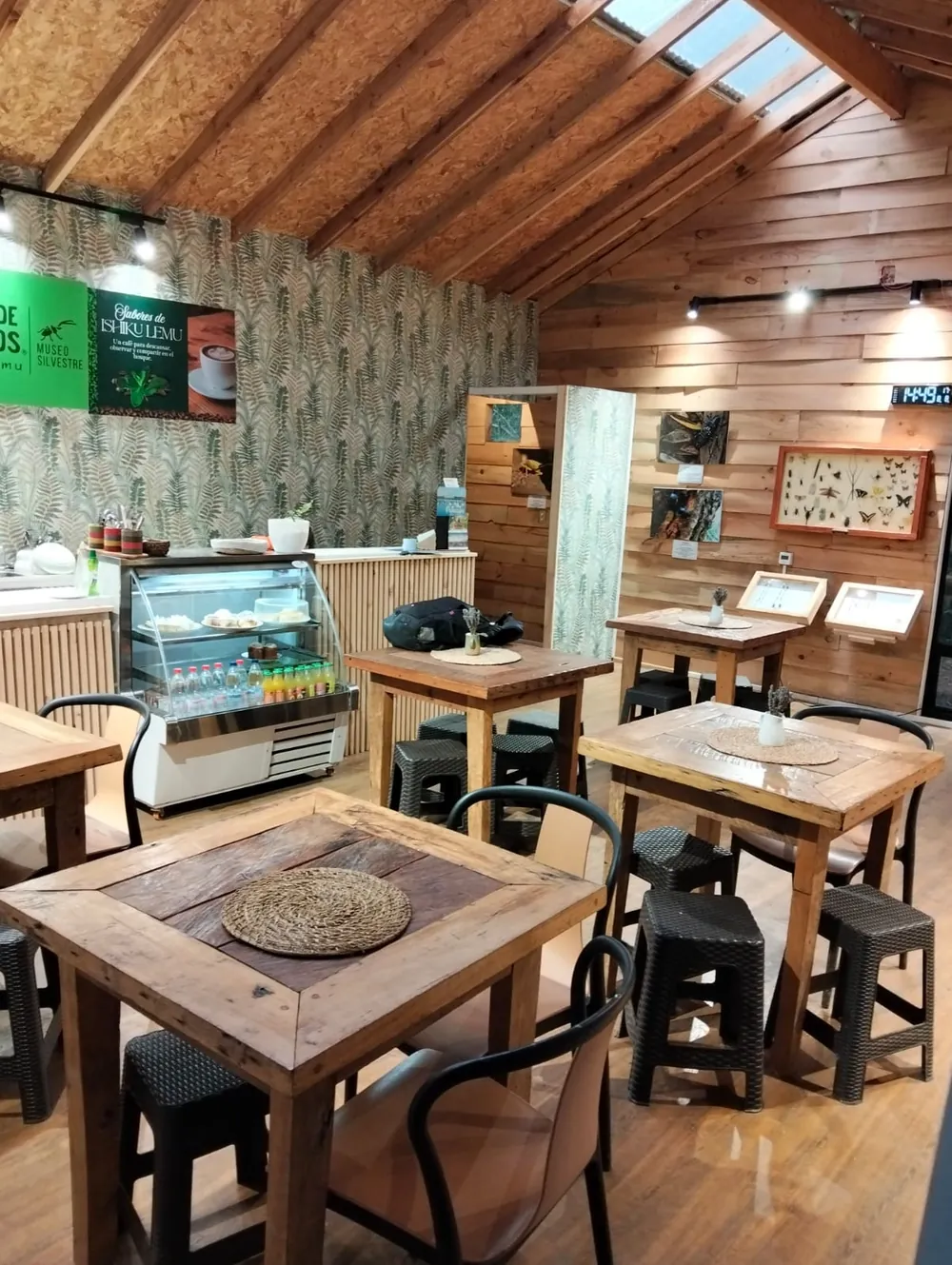 Interior de la Cafetería del Bosque, con mesas de madera y vitrina